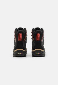 Svart og grå høye sneakers med teksturerte mønstre, røde detaljer og en fargerik såle. Har forsterkede snorer og polstret interiør.