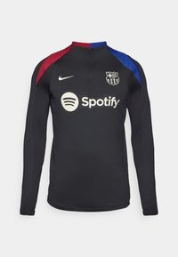 Schwarzes Sportoberteil mit langen Ärmeln und einem halb-zip-Kragen, mit roten und blauen Schulterakzenten, 'Spotify'-Logo und Teamwappen.