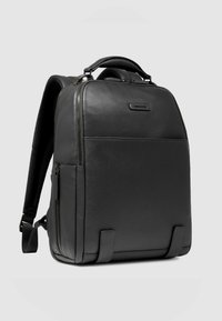 Zwarte leren rugzak met een gestructureerd oppervlak, een bovenste handvat, verstelbare banden en met rits afsluitbare compartimenten voor veilige opslag.