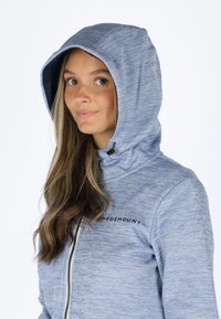 Light blue zip-up hoodie featuring a textured knit, adjustable hood, and logo on the left chest, combining comfort with functionality.