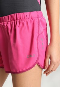 Pantalones cortos de running ligeros en color rosa con cintura elástica y un bolsillo lateral; presentan acentos oscuros en contraste y un logo grafito en el dobladillo.