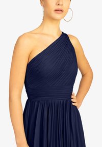 Marineblaues One-Shoulder-Kleid mit plissiertem Stoff, das einen taillierten Oberteil und einen fließenden Rock aufweist, entworfen mit einer definierten Taille und eleganter Drapierung.
