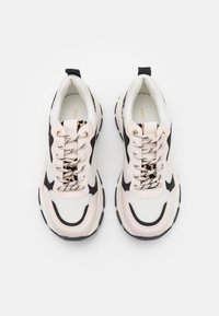 Baskets épaisses composées d'un mélange de mesh blanc et de matériau synthétique beige, avec des accents noirs et une languette à imprimé léopard. Semelles en caoutchouc noir.