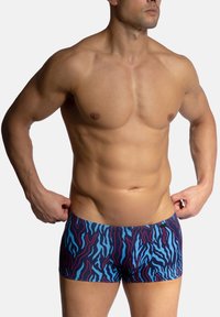 Plavky s přiléhavým střihem, s modro-burgundským abstraktním vzorem. Vyrobeny z hladkého materiálu s jemnou texturou.