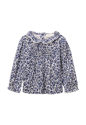 Blouse blanche à manches longues avec motif floral bleu, col à volants et détail smocké sur la poitrine.