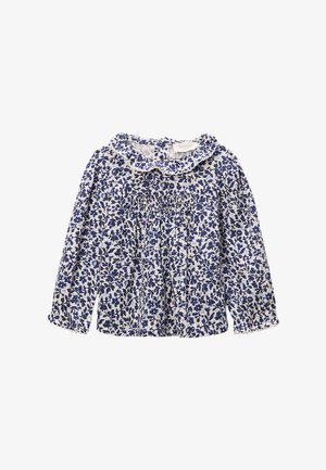 Blouse blanche à manches longues avec motif floral bleu, col à volants et détail smocké sur la poitrine.