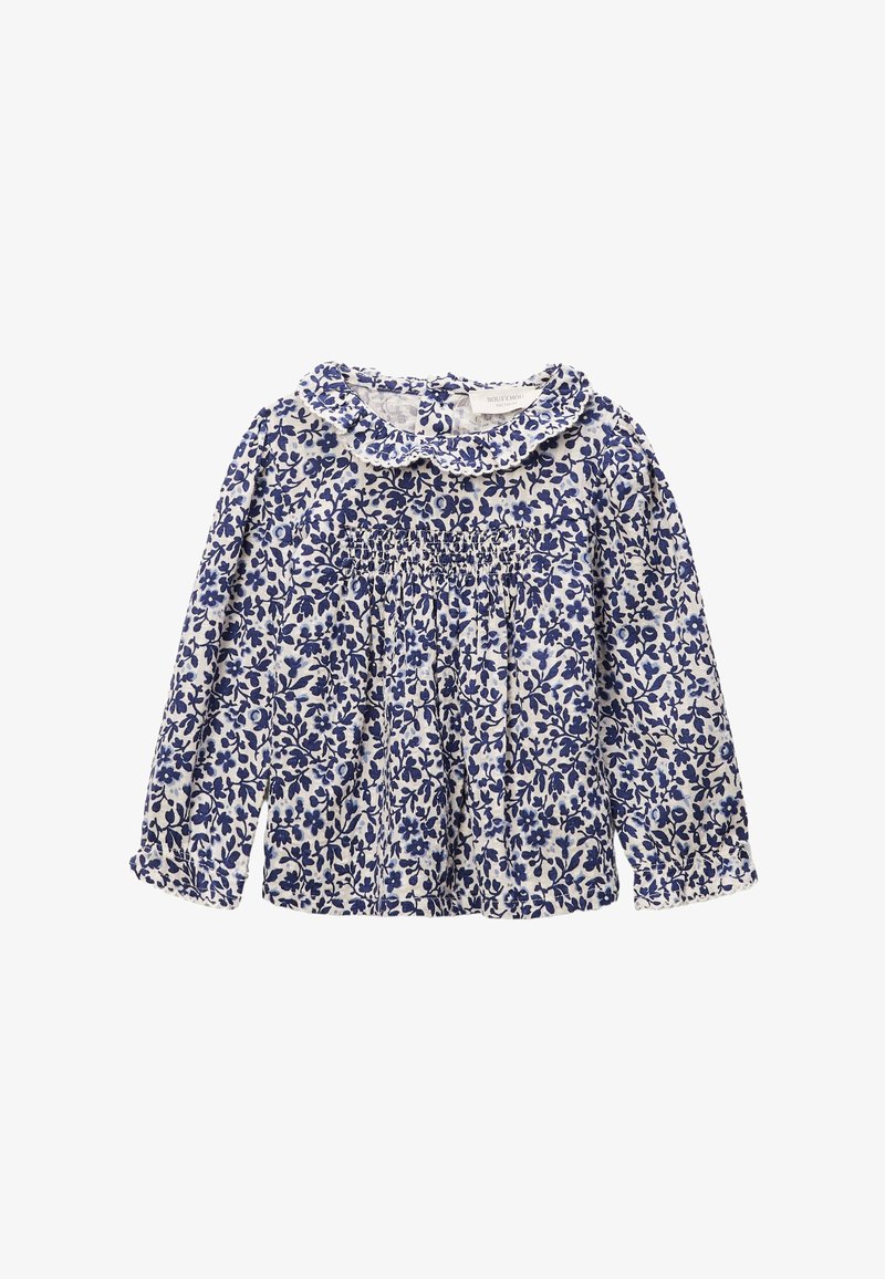 Blouse blanche à manches longues avec motif floral bleu, col à volants et détail smocké sur la poitrine.