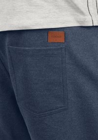 Navy siniset sweatpantsit, joissa on takataskussa nahkapatentti, jossa lukee "BLEND"; pehmeä rakenne ja yksi takataskun yksityiskohta.