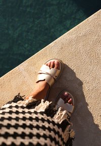 Světle zlaté sandály s dvojitým páskem, hladkým povrchem a polstrováním. Nosit s třásňovým černobílým vzorovaným oděvem.