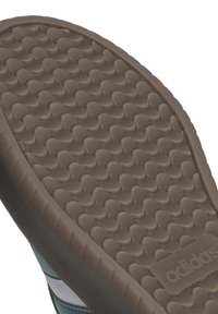 Suela de zapatilla de goma marrón con un patrón texturizado de formas redondeadas, que presenta un borde suave y la marca adidas.