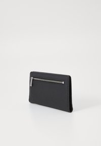 Portefeuille en cuir noir texturé avec un compartiment zippé visible, de forme rectangulaire et des bords lisses. Dispose d'un tirette de zip en métal argenté.