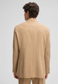 Hellbrauner, gestreifter Blazer aus strukturierter Stoffqualität. Mit Reverskragen, einer Schlitzöffnung und schmaler Passform. Rückansicht zeigt Detail des Musters.