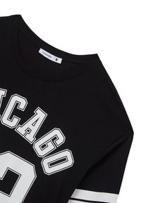 T-shirt nera in cotone, con la scritta "CHICAGO" in lettere bianche e grasse e il numero 9 bianco, con accenti a righe sulle maniche.