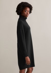 Schwarzes Turtleneck-Kleid aus weichem Stoff, mit lockerer Passform, gerippten Bündchen und Saum. Hat eine gerade Silhouette und ein mittellanges Design.