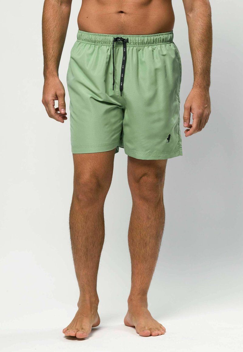 Bañador corto verde claro con cintura elástica, cordón negro y un pequeño logo en la pierna izquierda. Textura suave, corte hasta la rodilla.