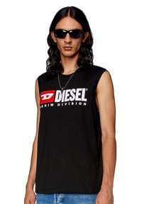 Črna brezrokavnik majica s bold belo in rdečo "DIESEL" logo in "DENIM DIVISION" besedilom čez prsa. Kratek, sproščen kroj.