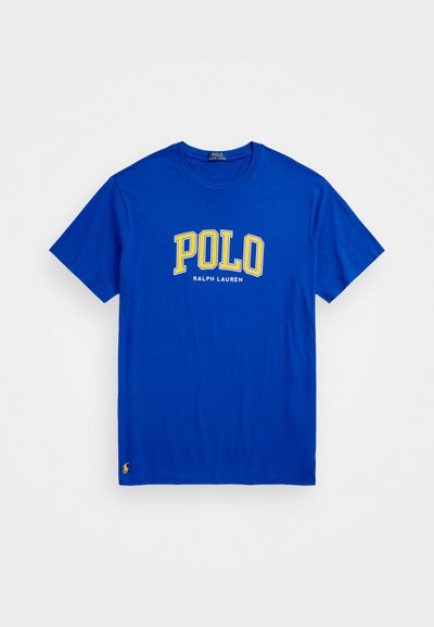Blue cotton t-shirt featuring "POLO" in large yellow letters and "RALPH LAUREN" in smaller text beneath. Includes a small logo on the lower hem.