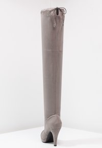 Wysoki, szary suede botek na obcasie z zaokrąglonym noskiem i sznurowaniem na górze z tyłu, wyeksponowany na białej powierzchni.