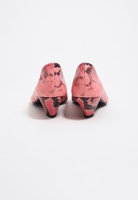 Zapatos de tacón alto con estampado de serpiente rosa, diseño de punta afilada, superficie texturada y un tacón negro corto. La vista posterior muestra contornos suaves.