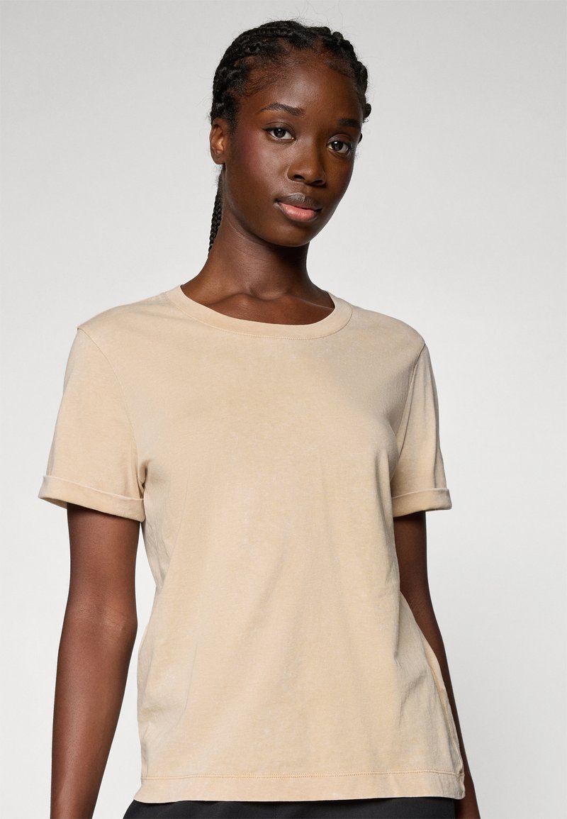 Beige T-Shirt mit kurzen Ärmeln aus weichem Baumwollgemisch, Rundhalsausschnitt und umgeschlagenen Ärmeln, mit lockerer Passform und subtiler Textur.