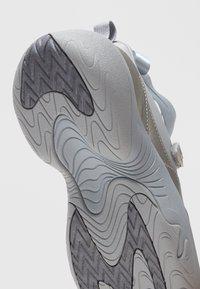 Σόλα ανοιχτογκρι αθλητικού παπουτσιού με υφή, κυματοειδή σχέδια πέλματος και πιο σκούρες γκρί ζιγκ-ζαγκ περιοχές για καλύτερη πρόσφυση.