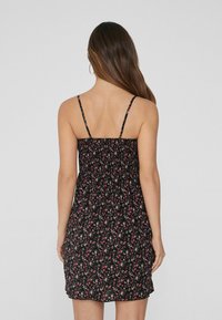 Schwarzes Blumenkleid mit verstellbaren Spaghetti-Trägern, elastischem Rücken und figurbetonter Silhouette. Hat kleine rote und grüne Blumenmuster.