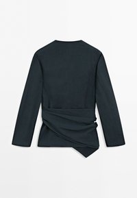 Black long-sleeve top with a draped, asymmetrical wrap detail at the waist, shown from the back on a white background.
