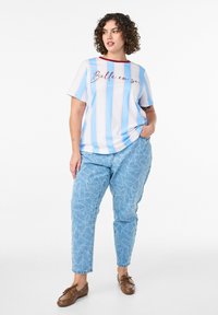 Värviline triibuline T-särk punase kaeluse ja tekstiga "Belle en soi", millele on sobitatud heledast sinisest denimi teksad südamemustritega.