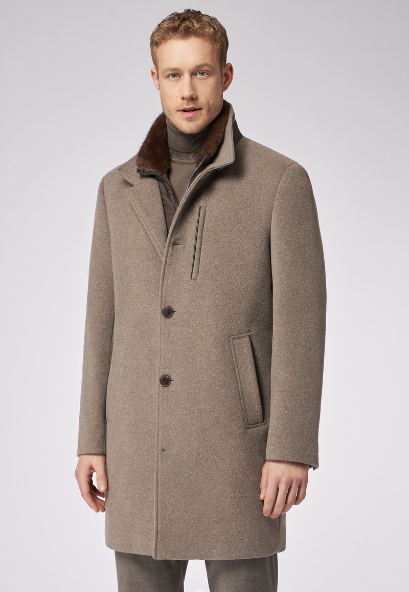 Cappotto da uomo in misto lana beige, con colletto foderato in pelliccia marrone, chiusura con due bottoni e tasca laterale, dal taglio aderente.