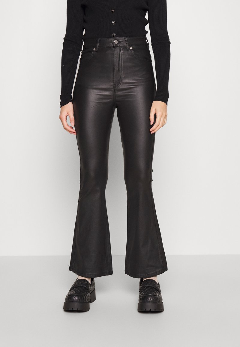 Calças flare de imitação de couro pretas com cintura alta, textura suave e costuras laterais discretas. Combinadas com sapatos pretos com padrão.