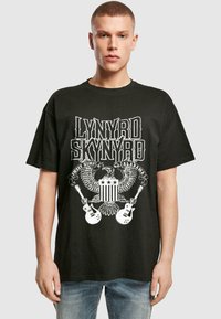 Sort t-shirt med et grafisk design, der har teksten "Lynyrd Skynyrd", enørn, guitare og stjerner. Den er lavet af bomuldsstof og har en afslappet pasform.