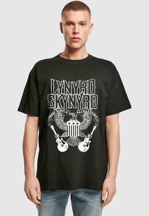 Fekete póló, amelyen grafikai minta található "Lynyrd Skynyrd" felirattal, egy sassal, gitárokkal és csillagokkal, pamut anyagból készült, laza szabással.