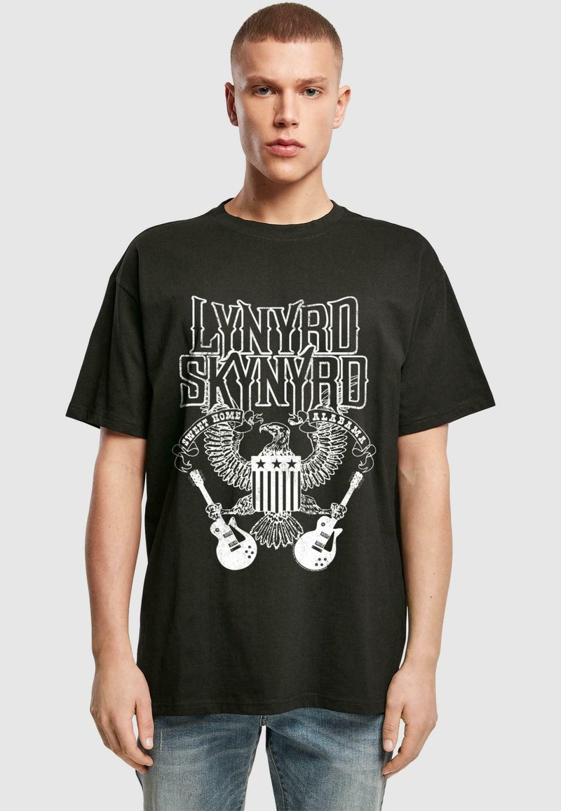 Sort t-shirt med et grafisk design, der har teksten "Lynyrd Skynyrd", enørn, guitare og stjerner. Den er lavet af bomuldsstof og har en afslappet pasform.