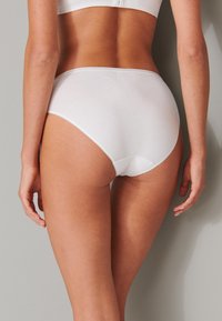 Braguitas hipster de algodón blanco con una textura suave y una cinturilla elástica, con un diseño sencillo sin patrones ni acentos visibles.