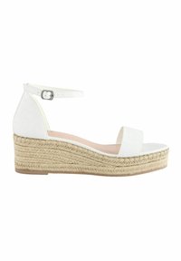 Sandalia de cuña blanca de espadrille con un patrón texturizado de cocodrilo, correa ajustable en el tobillo y plantilla de yute trenzado. Suela plana.