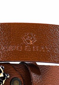 Cintura in pelle marrone con logo impresso. Presenta una superficie testurizzata e un accento metallico decorativo con uno chiodo centrale.