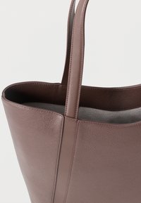 Brązowa skórzana torba na ramię z teksturowaną powierzchnią i gładkimi akcentami. Posiada dwa solidne uchwyty oraz otwarty design u góry.