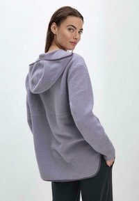 Lila Fleece-Hoodie mit Kängurutasche und abgerundetem Saum, ausgestattet mit einer Schnürkapuze und strukturiertem Stoff.