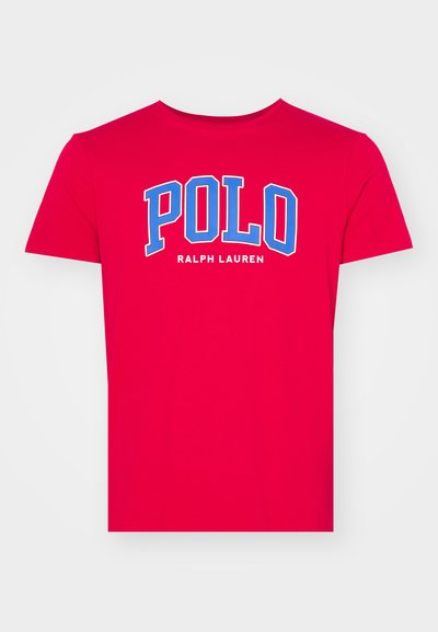 Piros pamut póló, kerek nyakú és rövid ujjú. A mellkason nagy kék betűkkel "POLO" látható, míg az "RALPH LAUREN" kisebb betűkkel van feltüntetve.