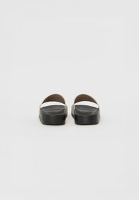 Sandale slip-on negre și gri, cu o suprafață netedă, curele late și tălpi plate. Logo-ul brandului este embosat pe lateral.