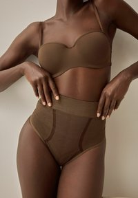 Bruine lingerie set met een gevoerde, strapless bh en hoogsnijdende shapewear met een soepele textuur en gedetailleerde patronen.