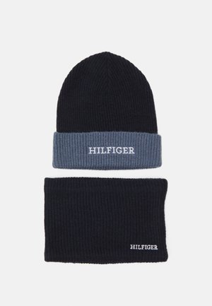 Set di berretto e scaldacollo lavorati a maglia in blu scuro e azzurro chiaro. Presentano una texture a costine; entrambi gli articoli mostrano il logo "HILFIGER" in bianco.