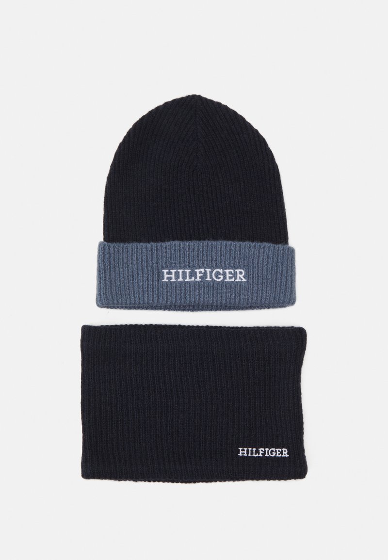Set di berretto e scaldacollo lavorati a maglia in blu scuro e azzurro chiaro. Presentano una texture a costine; entrambi gli articoli mostrano il logo "HILFIGER" in bianco.