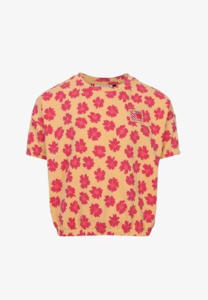 Geel shirt met korte mouwen en elastische zoom, bedekt met een helder roze bloemenpatroon en een kleine rode patch op de bovenste linkerborst.