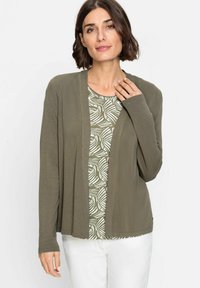Olivgrüner, offener Cardigan mit langen Ärmeln über einem gemusterten Oberteil. Der Cardigan hat eine glatte Textur und eine lockere Passform.