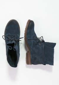 Granatowe zamszowe botki za kostkę z okrągłym noskiem, z przodem sznurowanym i brązową gumową podeszwą. Posiadają akcenty w postaci przeszyć oraz miękkie wykończenie wnętrza.