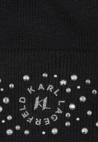 Bonnet tricoté noir avec un logo circulaire portant le texte "KARL LAGERFELD", orné de cristaux en strass argentés de différentes tailles pour la décoration.