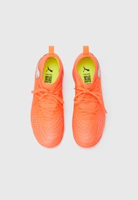 Lyse orange sportssko med tekstureret overflade, matchende snørebånd og limegrøn indersål. Har et Puma-logo og en QR-kode.