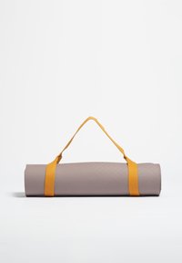 Esterilla de yoga morada mate enrollada, con una superficie texturizada y sujeta con una brillante correa amarilla para facilitar su transporte.