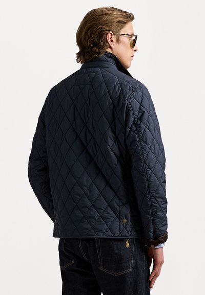 Marineblaue gesteppte Jacke mit hohem Kragen, Rautenmuster und Druckknöpfen am Saum. Glatte Textur mit weicher Fütterung.